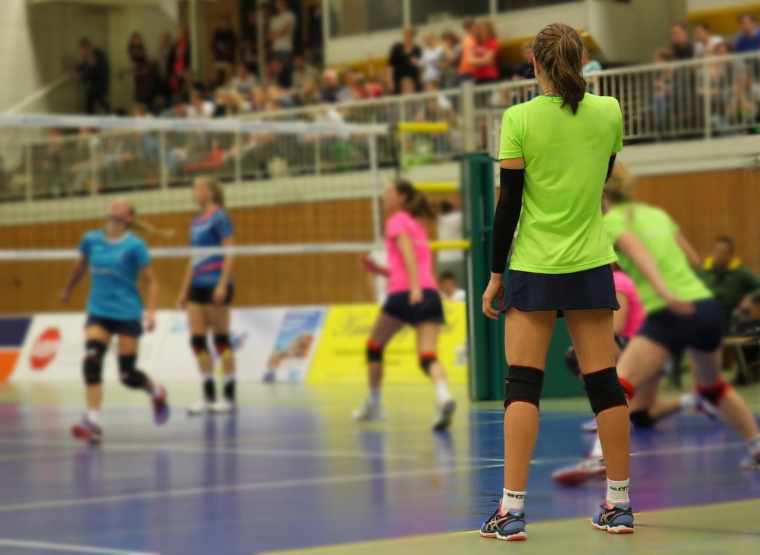 Niñas entrenando voleibol con camisas de colores