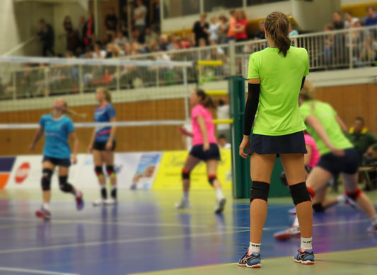 Niñas entrenando voleibol con camisas de colores